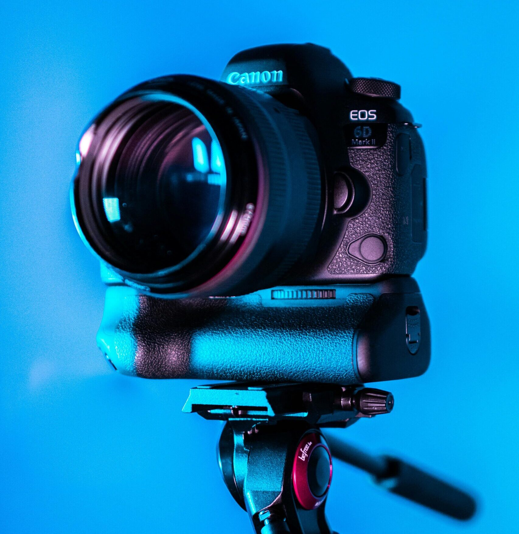 Close-up of a DSLR camera on a tripod with a blue background.